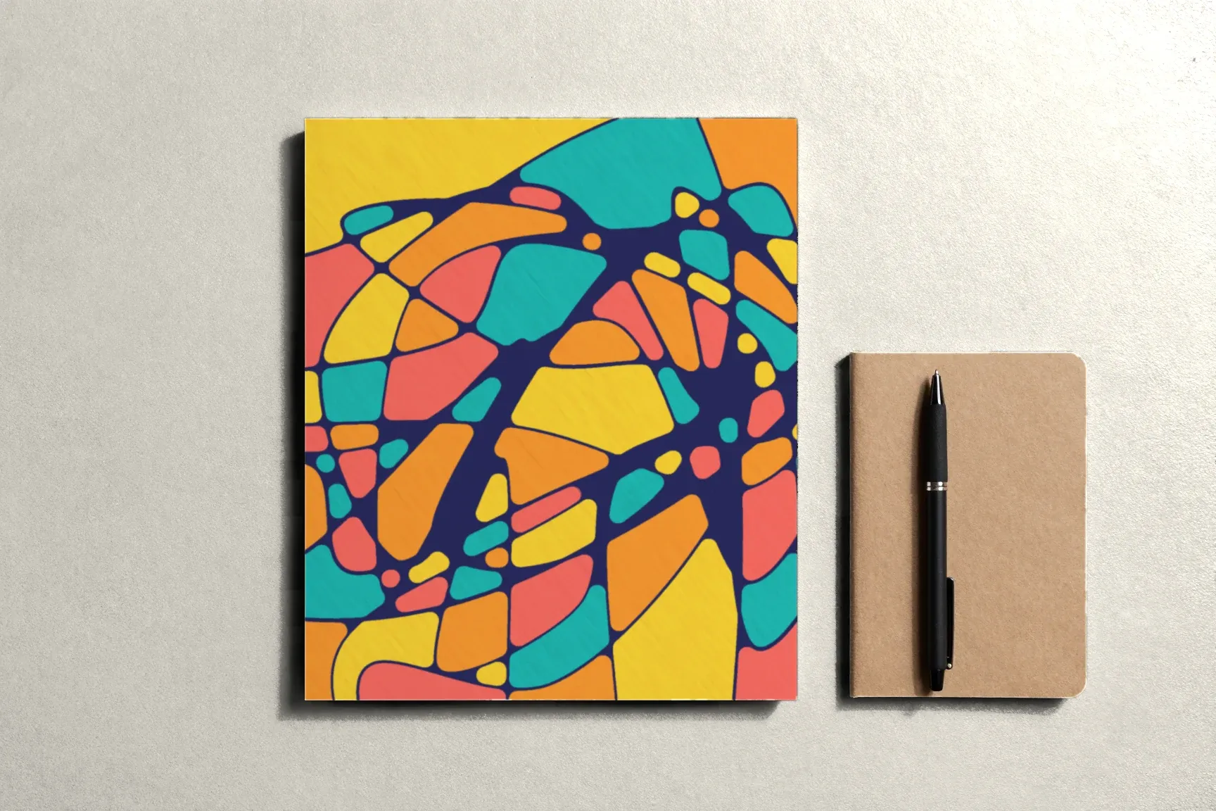 A finished drawing and a small kraft-covered notepad with a pen on it.